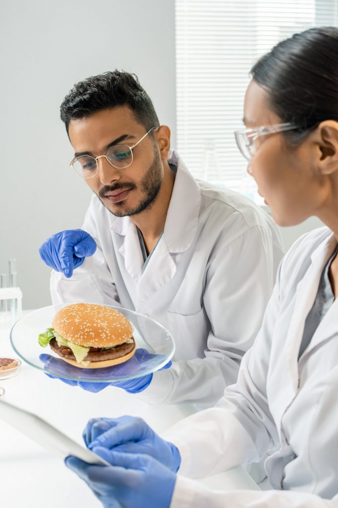 Male worker of food quality control pointing at hamburger with vegetable meat